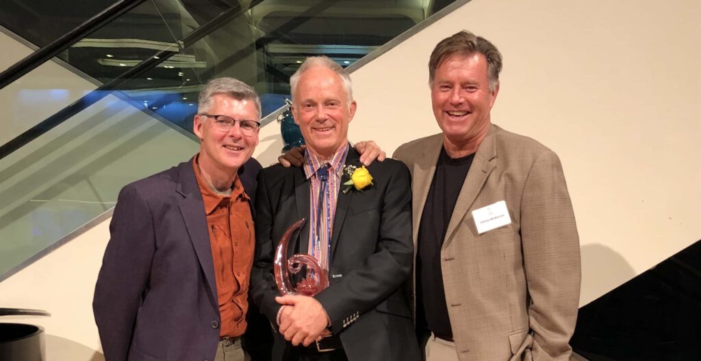 David Chantler dressed in a black blazer suit poses for the camera with Scott and Dennis by his side at the Rozsa Awards 2017