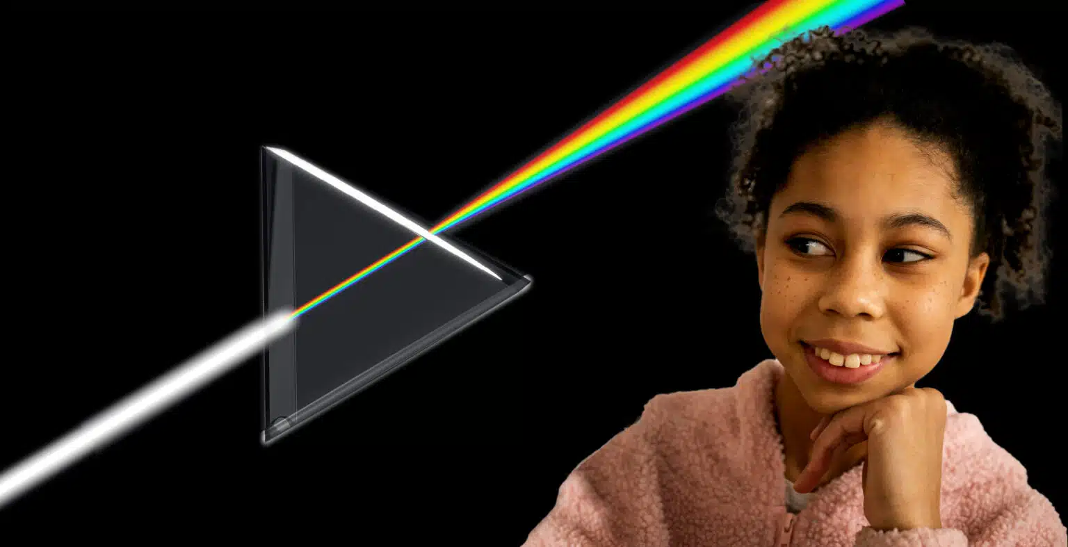 Little girl in a pink jumper looks at light passing through a transparent prism object