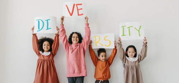 Four children hold up letters that spell diversity on white paper