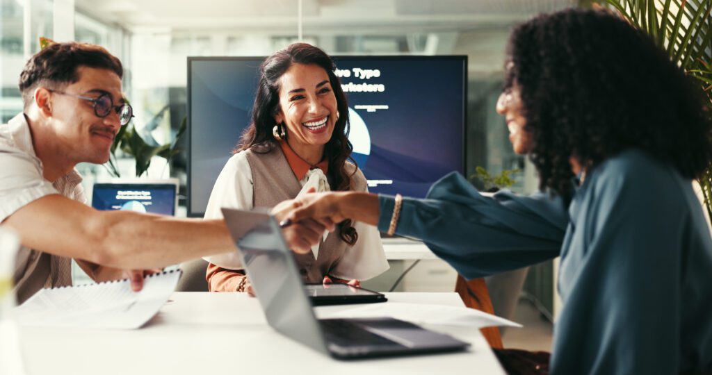 Happy business people, startup and shaking hands for deal, brand sponsorship or collaboration. Smile, creative team and handshake for cooperation, b2b partnership and negotiation agreement in office.